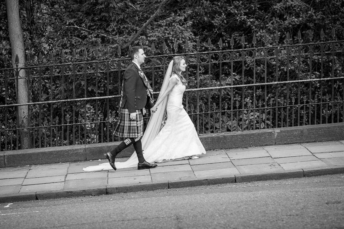 newlyweds walking up Queen Street Gardens East viewed from the opposite side of the road