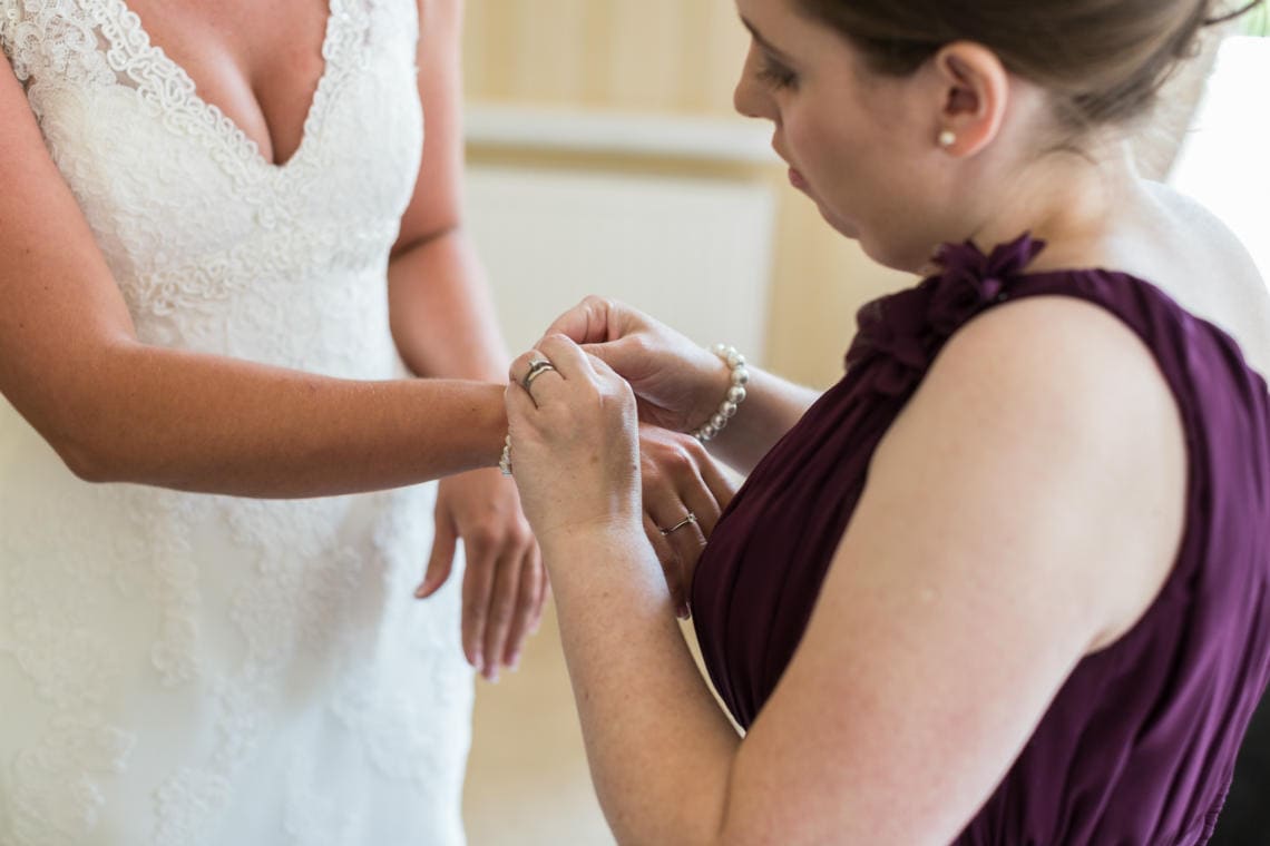 brdiesmaid helps bride put on a bracelet