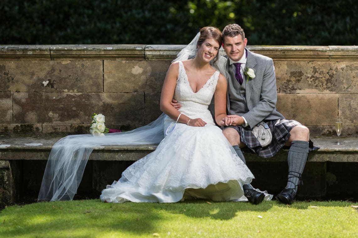 newlyweds sitting on the stone seat in the garden