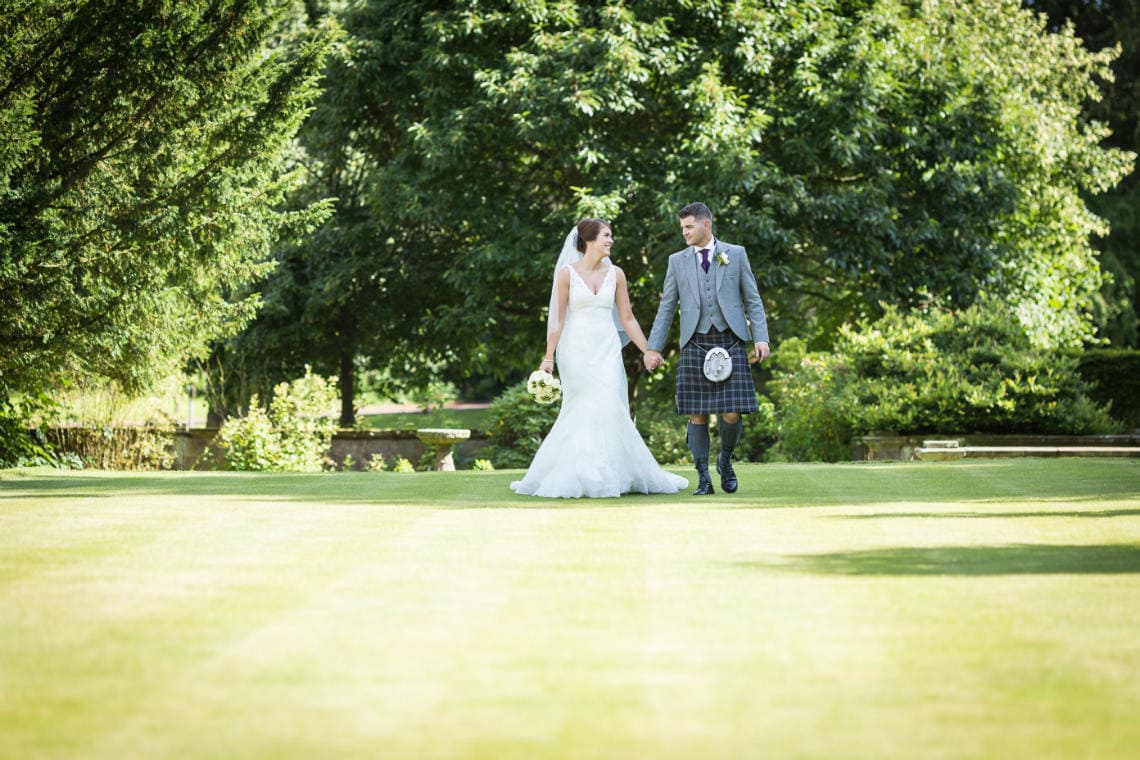 newlyweds walking hand in hand on the lawn