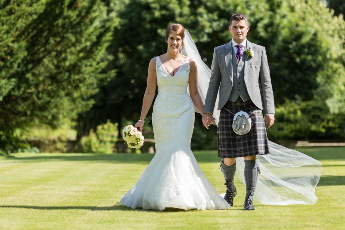 newlyweds walking hand in hand on the lawn
