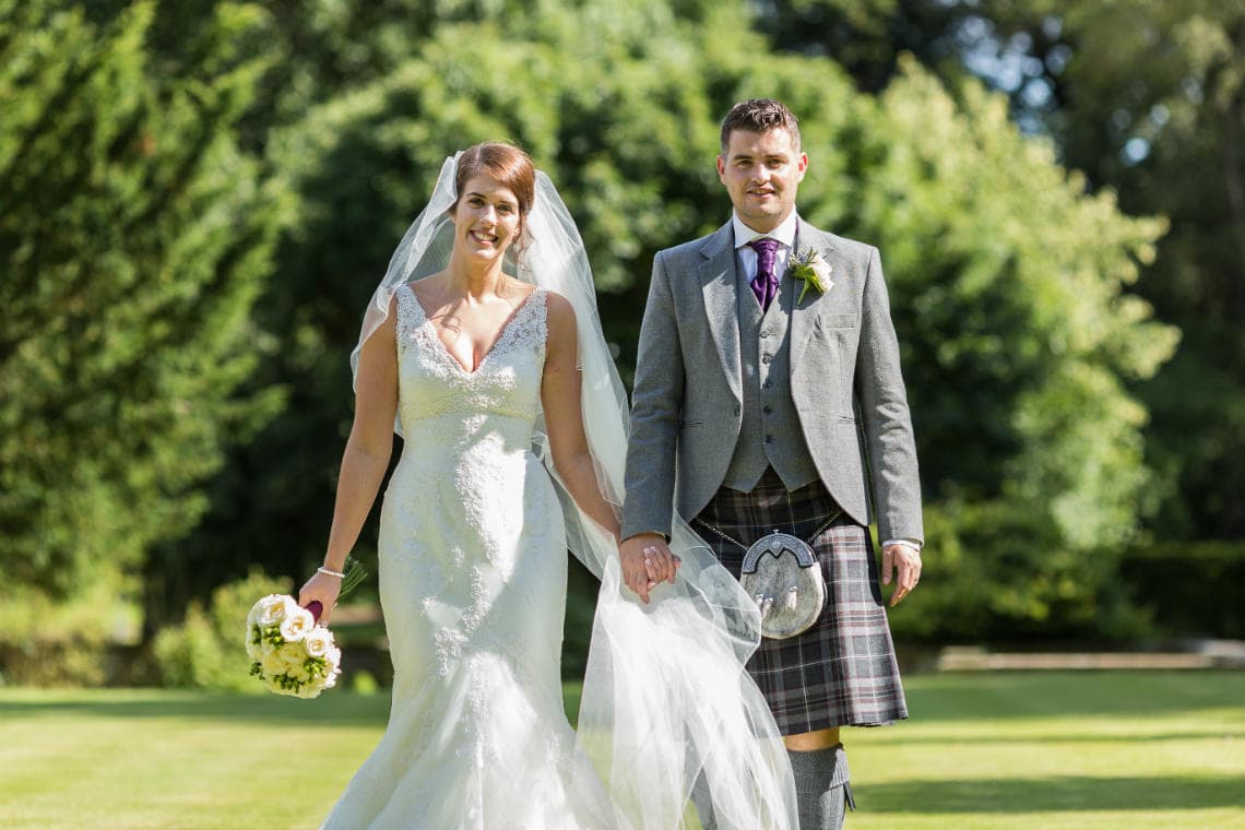 newlyweds walking hand in hand on the lawn