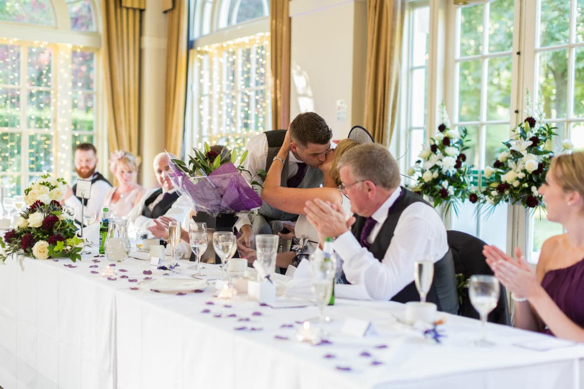 groom presents flowers to mother