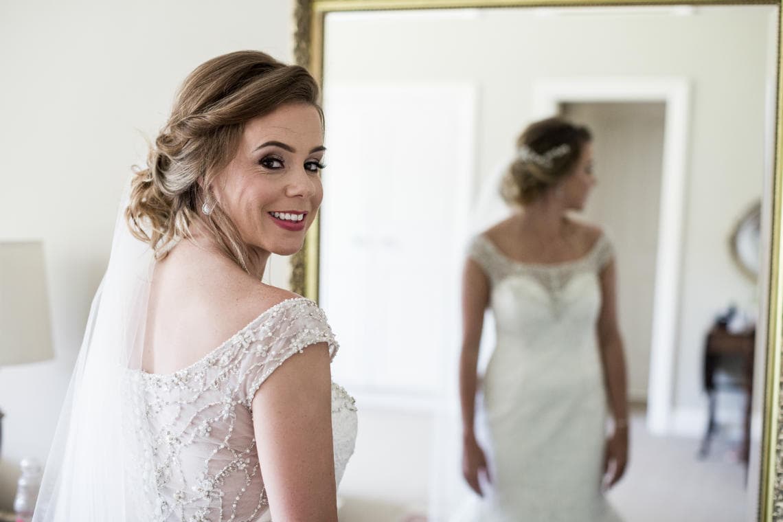 posed photo of bride standing in front of a mirror in house