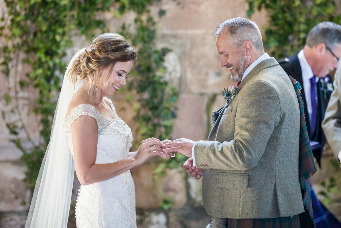 bride places ring on groom's finger during ceremony in church