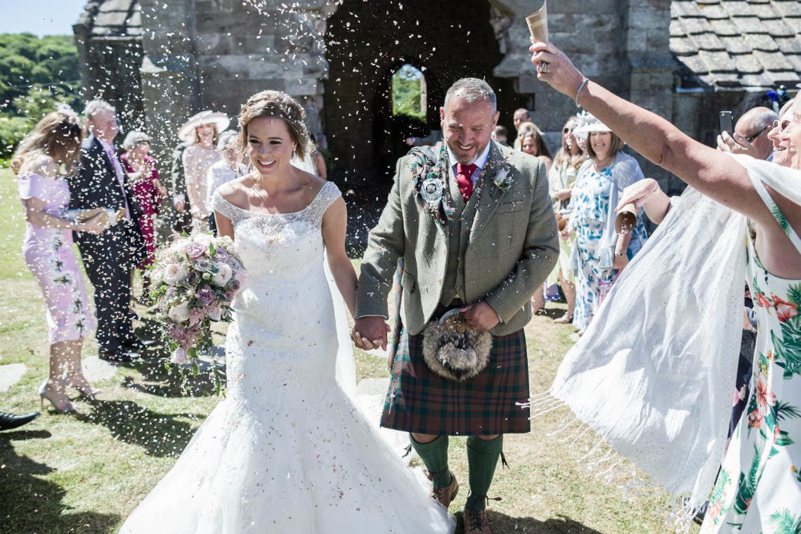 newlyweds during confetti shower outside church