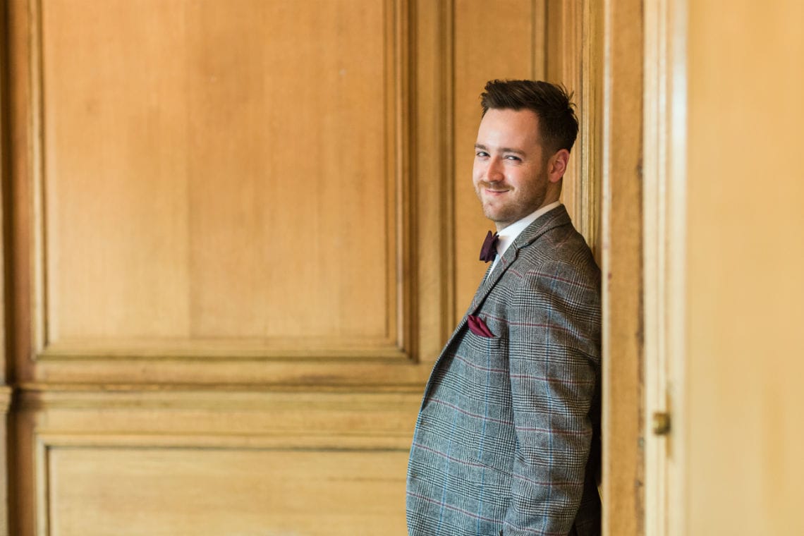 Groom leaning against panelled wood wall in the Boardroom