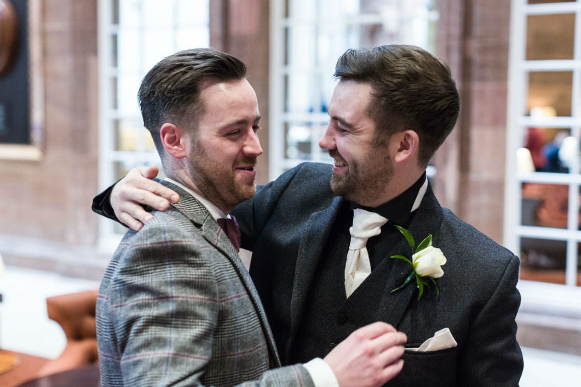 Man hugging Groom in Peacock Alley
