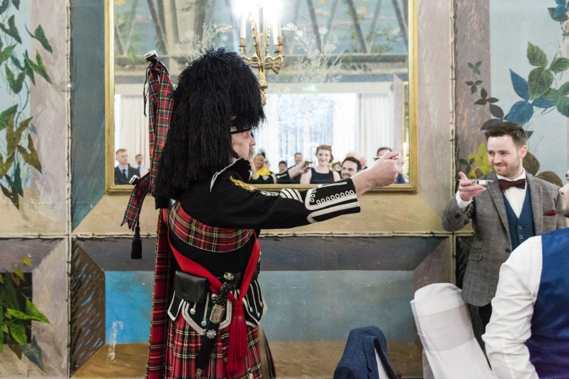 Piper standing holding a sliver quaich