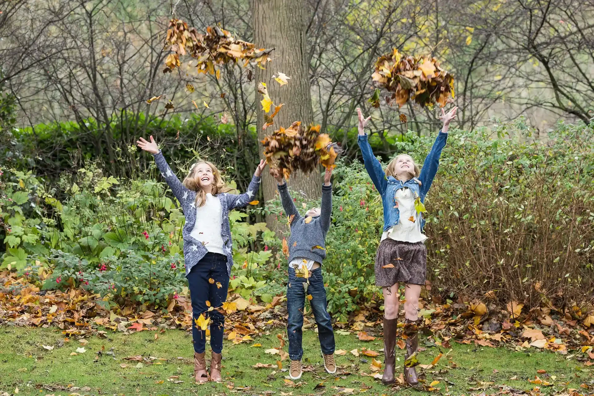 kids throwing autumn leaves in Princes Street Gardens - Family photographer in Edinburgh