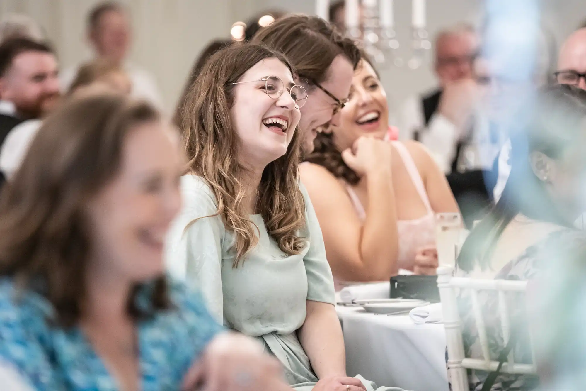 People seated at a formal event, smiling and laughing.